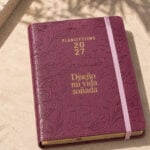 agenda de piel Planifesting 2027 en Borgoña con flores en relieve, elástico rosa y frase Diseño mi vida soñada en dorado