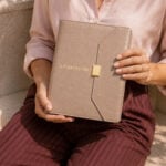 agenda de carpeta Planifesting 2027 beige croco sostenida por una mujer sentada al aire libre