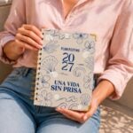 agenda espiral beige 2027 mujer sosteniendo la agenda con blusa rosa