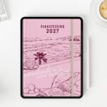 agenda digital Planifesting 2027 abierta en tablet con lápiz digital junto a una taza de café
