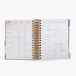 Agenda espiral 2026 rosa con morado abierta en calendario mensual