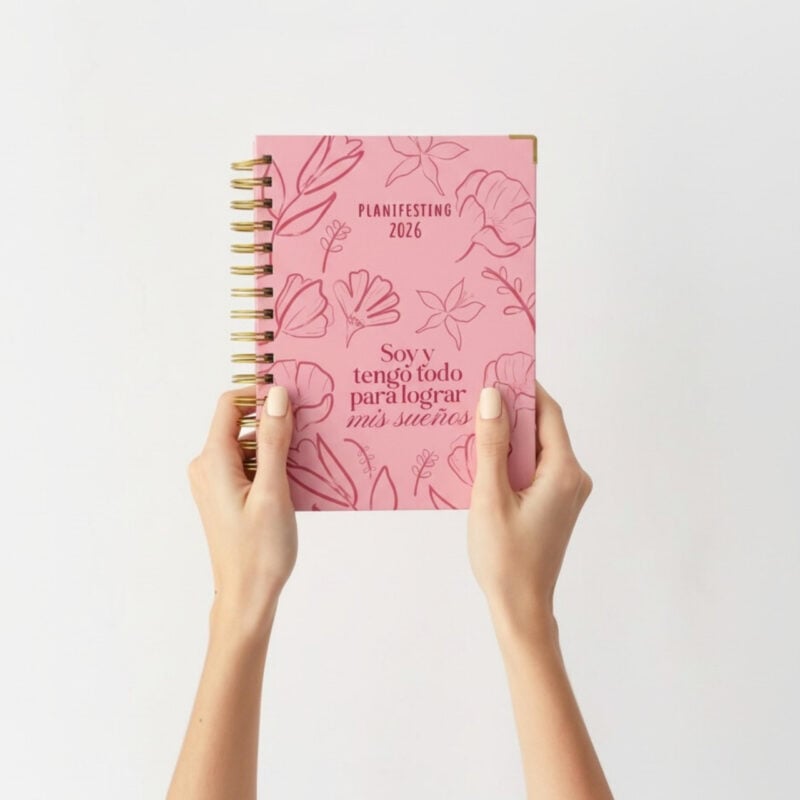 Agenda Planifesting 2026 rosa con flores sostenida con ambas manos fondo blanco