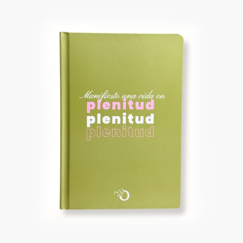 Libreta color verde con la frase "Manifiesto una vida en plenitud" en tipografía rosa y blanca.