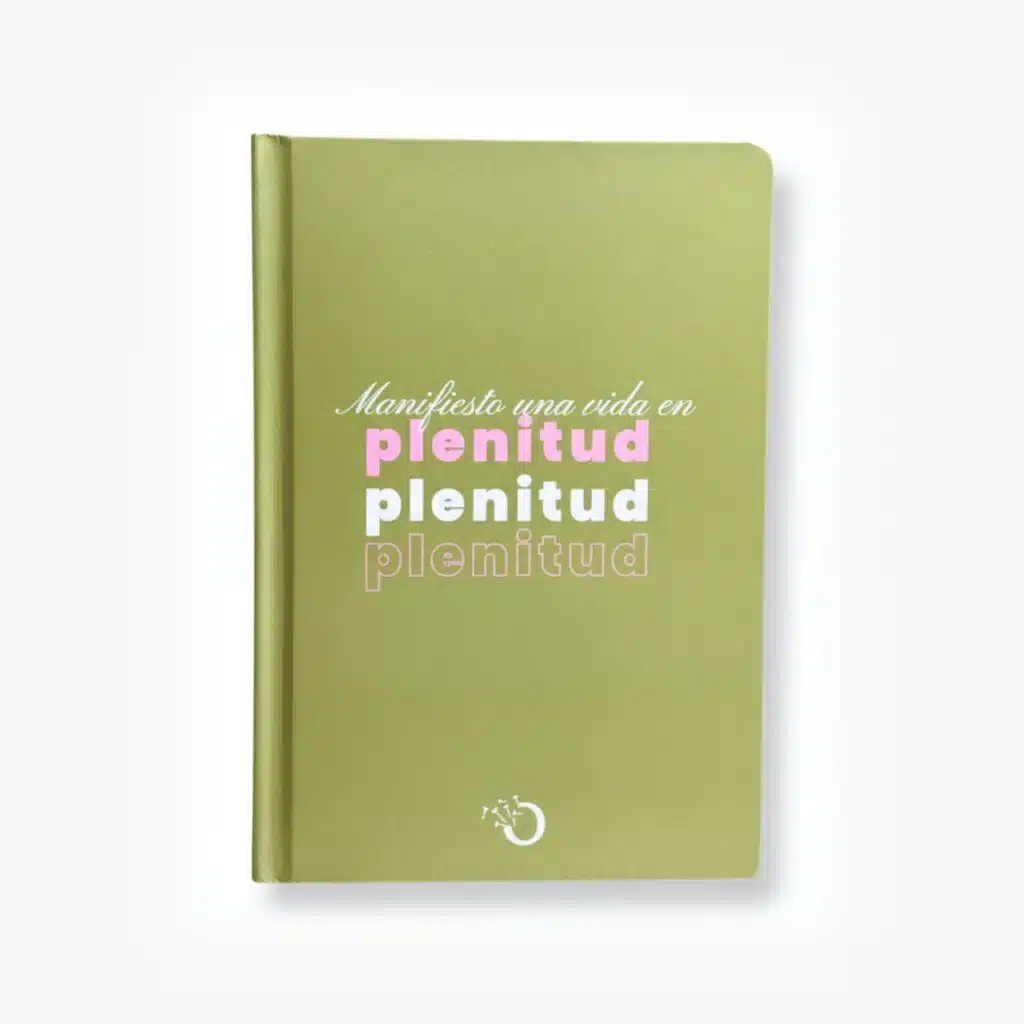 Libreta color verde con la frase "Manifiesto una vida en plenitud" en tipografía rosa y blanca.