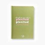 Libreta color verde con la frase "Manifiesto una vida en plenitud" en tipografía rosa y blanca.