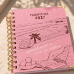 agenda de pasta dura Planifesting 2027 rosa "aprendiendo a vivir en calma" sobre superficie de piedra con luz natural