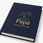Acercamiento al foil dorado en alto relieve de Cartas de Papá con montañas, aves y "El libro de mi vida"