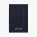 Contraportada en tela azul marino con logo dorado de OREM un estilo de vida y cierre elástico